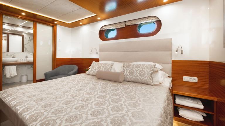 Eine Kabine mit gemütlichem Doppelbett mit einem Badezimmer aus weissen Mamor.
